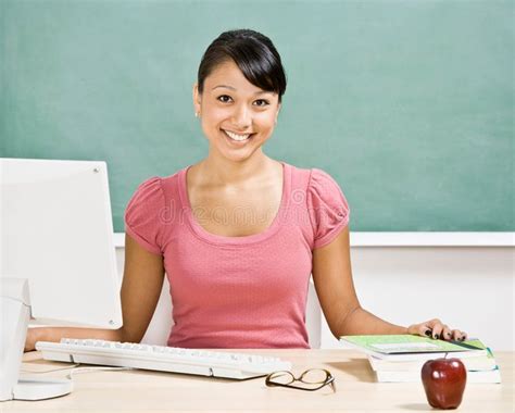 Teacher At Desk In Classroom Happy Teacher Sitting At Desk With