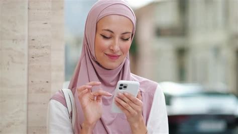 a positive arabian woman wearing pink national hijab is using her phone stock footage