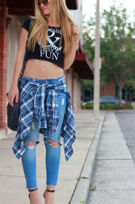 90s clothes womens cropped black t shirt with white print ripped jeans and a flannel shirt