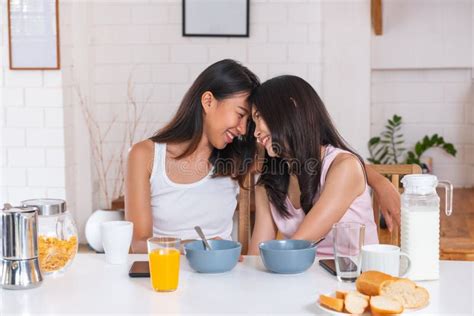 casal de lésbicas asiáticas felizes assistindo televisão juntos no sofá na sala de estar de