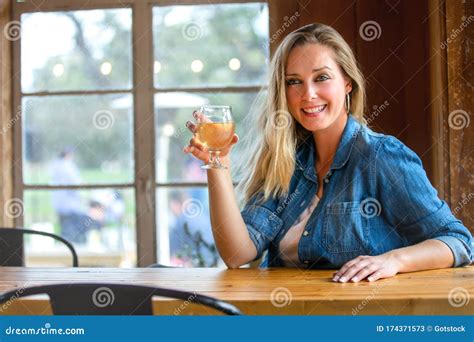 Portrait Of A Woman In A Taproom Drinking Tap Draft Pints Of Craft Beer Or Cider Wine Stock