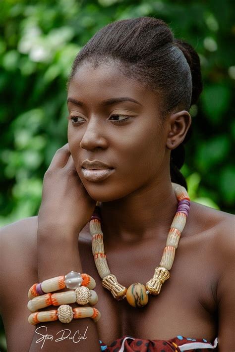 An African Woman With Beads And Bracelets On Her Neck Looking At The Camera While Standing In