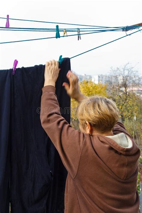 laundry woman hangs clean wet cloth on clothes dryer after washing at home household chores and