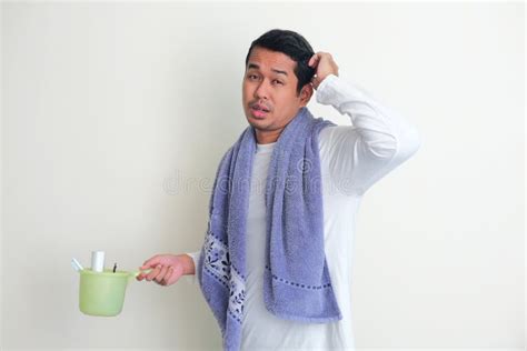Side View Of Adult Asian Man Scratching His Head While Bring Towel