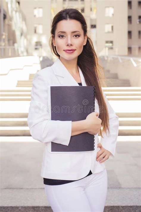 Beautiful Brunette Business Woman In White Suit With Folder Of Documents In Her Hands Outdoors