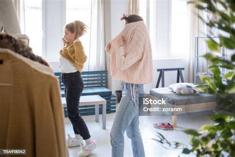 Young Women Getting Dressed In Sweaters Stock Photo Download Image