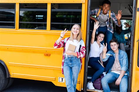 Group Of Teen Scholars Sitting At School Bus With Driver