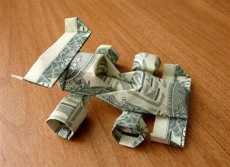 An Origami Airplane Made Out Of Dollar Bills On A Table With Wood