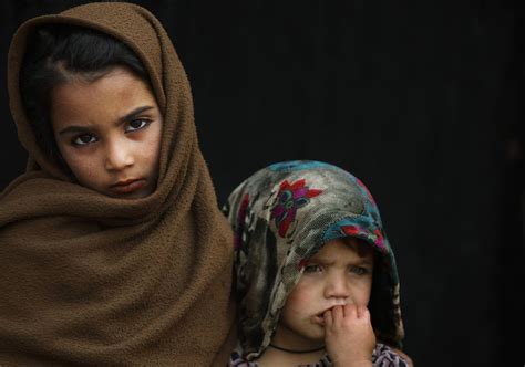 An Afghan Refugee Girl Looks On While Standing With Her Sister Outside