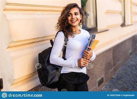 Female College Student With Books Outdoors In The Street Smiling
