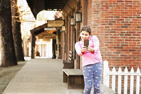 Mixed Race Girl Taking Selfie On Sidewalk Photo12 Tetra Images Sollina Images