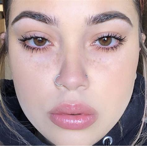 a close up of a person with piercings on her nose