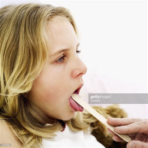 Side View Of A Young Girl Having A Throat Examination With A Tongue