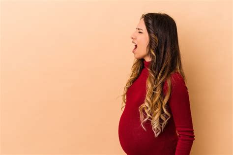 joven mujer embarazada mexicana aislada en la pared beige riendo y divirtiéndose foto premium