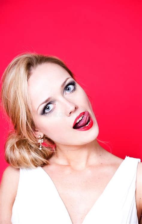 Caucasian Woman Wearing White Dress On Red Background Licking Her Lips