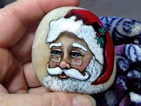 A Hand Holding A Rock With A Santa Clause Painted On Its Face And