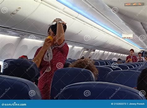 a female flight attendants on the aisle show passengers about safety instruction on board with