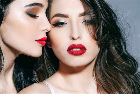赤い唇を持つセクシーな官能的な女性レズビアンのカップルのキス唇官能的な唇のキス2人の美しいセクシーなレズビアンの女性の美しさの女性の顔の肖像画のクローズアップ プレミアム写真