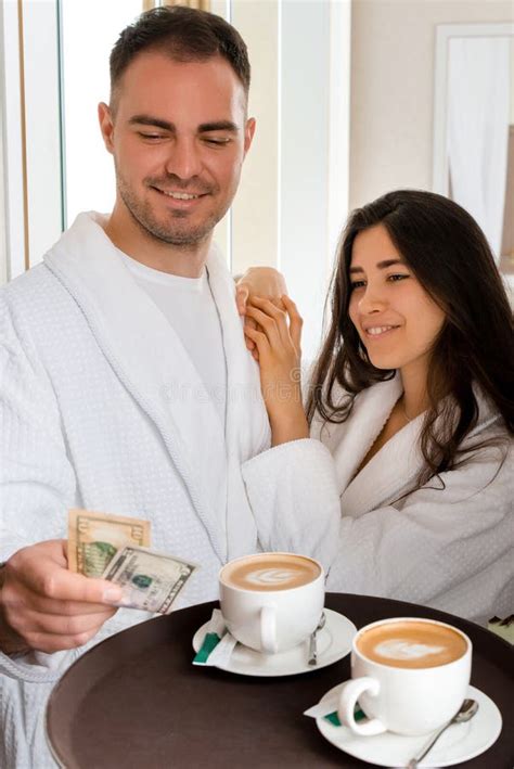 Room Service Delivering 2 Cups Of Coffee To A Hotel Room For Married Couple Lying In A Bed In
