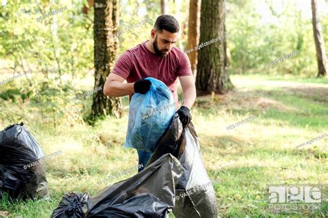 Male Volunteer Putting Waste In Garbage Bag Stock Photo Picture And