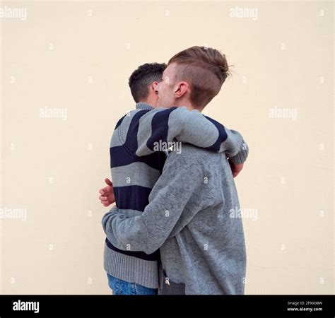 Young Interracial Gay Couple Hugging Isolated On A Beige Background