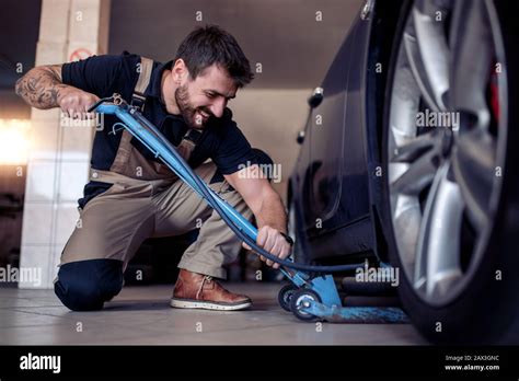 Professional Auto Mechanic Changing A Tire In Auto Repair Shop Man Changing Car Wheel In Auto
