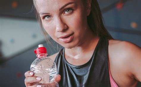 Tired Fitness Girl Drinking Water And Resting After Workout In Gym