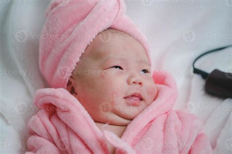 Closeup Cute Newborn Baby In Pink Bodysuit Lying Down Alone On Bed