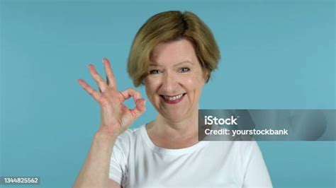 Okay Sign By Old Woman Isolated On Blue Background Stock Photo