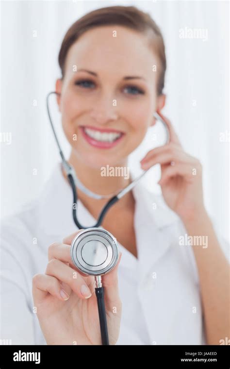 Smiling Pretty Nurse Posing Holding Her Stethoscope In Bright Office