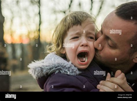 Father Kissing His Crying Little Daughter And Comforting Her In Nature