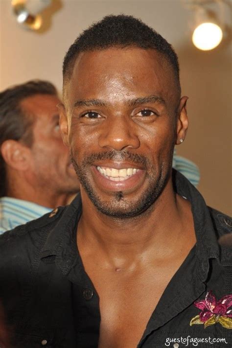 A Close Up Of A Person Wearing A Black Shirt And Smiling At The Camera With Other People In The