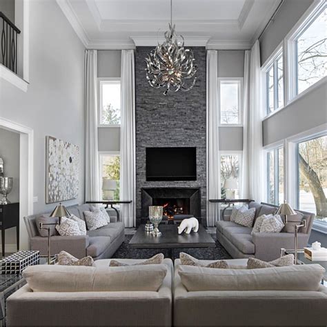 Turquoise chairs break up the neutrals, as does a colorful accent pillow on the sofa. Grey stone fireplace | Elegant living room decor, Elegant ...