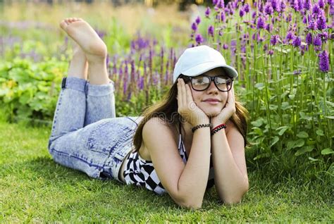 A Young Girl Is Lying With Bare Feet On The Green Grass Near The Flowers Stock Image Image Of
