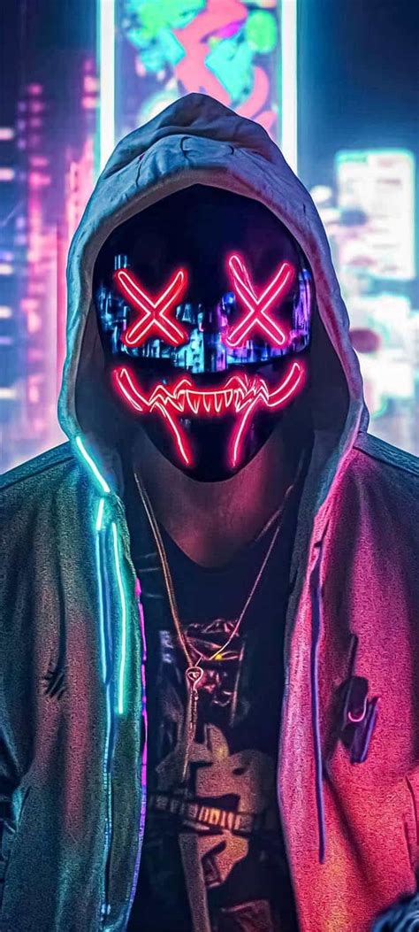 A Man Wearing A Neon Mask And Hoodie In Front Of A Cityscape