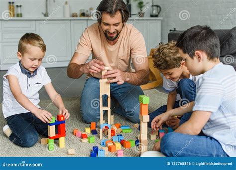 Cheerful Father And Kids Playing With Wooden Blocks Together On Floor