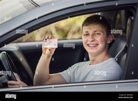 Happy And Proud Guy Showing His Driver License Out Of The Car Window