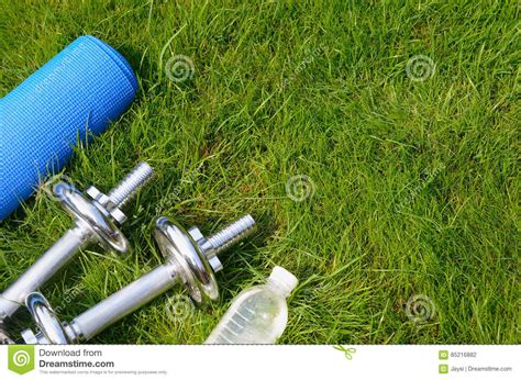 fitness en gezond levensstijlconcept sportschoenen domoren fles water en mat op gras stock