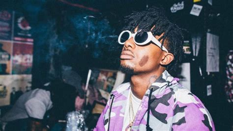 Playboi Carti Is Looking Up Wearing Purple And Black Coat With White
