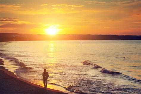 Man Walking Alone On The Beach At Sunset Calm Sea Stock Image Image