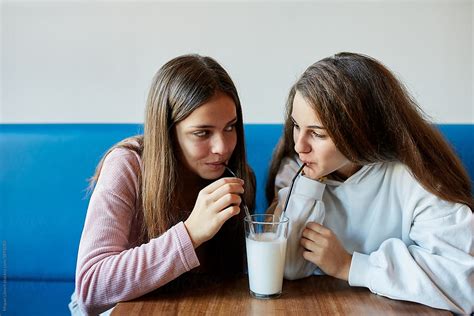 Girlfriends Sharing A Glass Of Milk Or White Drink By Stocksy