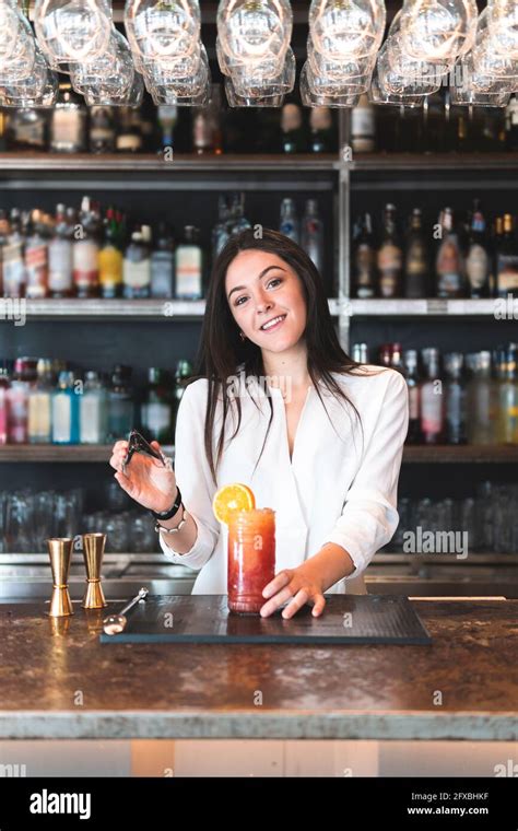 Smiling Beautiful Female Bartender Holding Serving Tong At Bar Counter