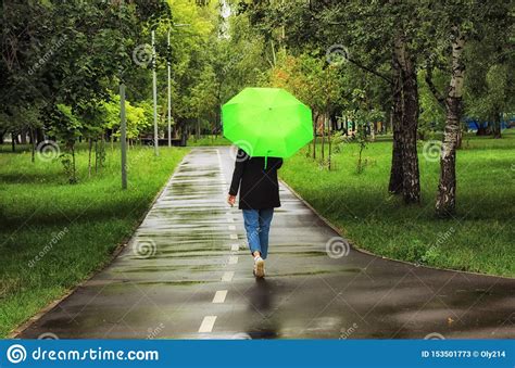 Young Beautiful Girl Walking Alone Under Green Umbrella In The City Park In Summertime Stock