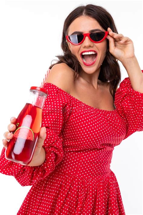 Stylish Brunette Girl In Sunglasses With A Glass Of Cocktail Is Dancing On A White Background