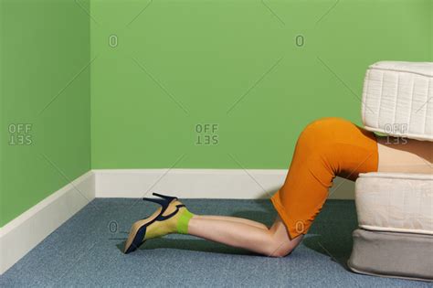 Woman Kneeling On Floor With Upper Body Between Mattresses Stock Photo