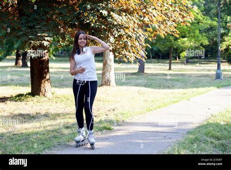 Junge Schöne Frauen Auf Rollschuhen In Den Park Fahren Und Sehen Der Umgebung Stockfotografie