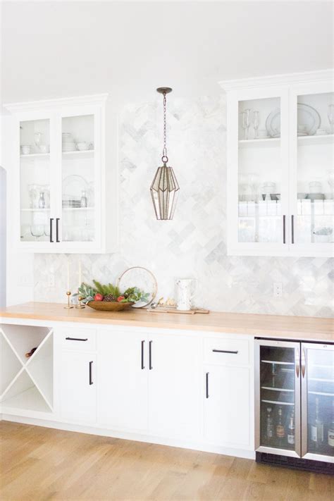 A Kitchen With White Cabinets And Wood Flooring Next To A Wine Rack