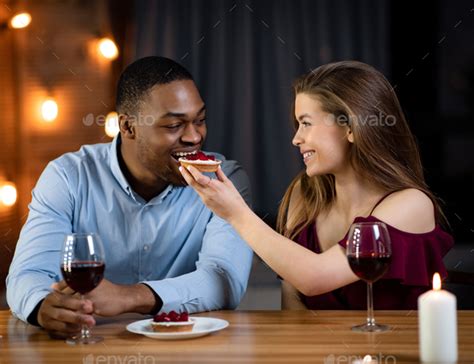 Romantic Interracial Couple Having Dinner Date In Restaurant Feeding