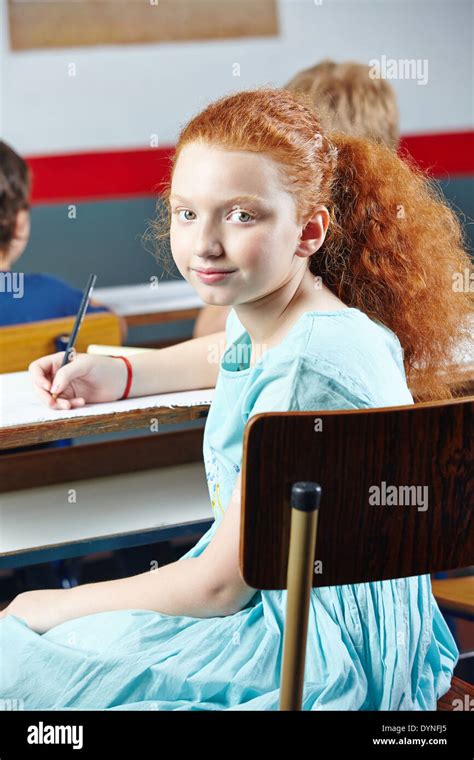 Female Student Sitting In Elementary School Class At A Table Stock