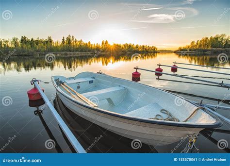 Calm Lake With Reeds At Sunrise Fishing Boat Tied To Wooden Pier Stock